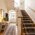 A hallway with a staircase that has handrails attached and a carpet for support.